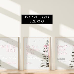 May include: Three printable 8x10 inch signs for a baby shower game. The signs feature a wintery forest scene with a pink ribbon and text that reads "Pacifier Hunt", "How big is Mommy's Belly?" and "Guess the Baby Food".