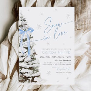 May include: A blue and white winter-themed bridal shower invitation with a watercolor illustration of a snowy pine tree decorated with a blue ribbon. The text reads "Snow in Love" and includes the bride's name, date, time, and location. The invitation also includes the text "Registered at Amazon and Target".