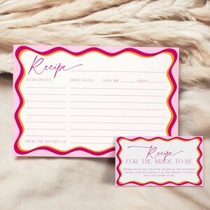 May include: Pink and orange recipe cards with a wavy border. The top card has a blank recipe template with headings for ingredients, directions, cook time, and serves. The bottom card has the text "Recipe for the Bride-to-Be" and instructions to write a favorite recipe on the enclosed card and bring it to the shower to share with the bride-to-be.