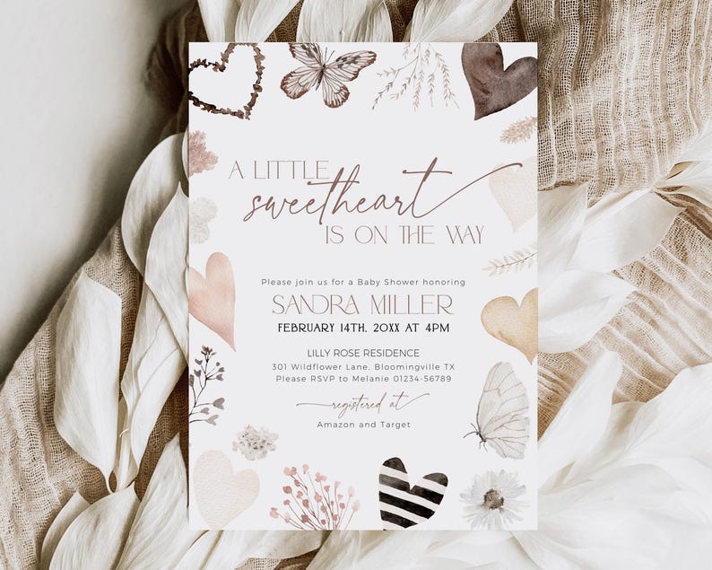 May include: A baby shower invitation with a watercolor design featuring butterflies, hearts, and floral elements. The text reads "A little sweetheart is on the way" and includes the name "Sandra Miller", the date "February 14th, 20XX", the time "4PM", the location "Lilly Rose Residence", and the address "301 Wildflower Lane, Bloomingville TX". The invitation also includes the RSVP information and the registry information.
