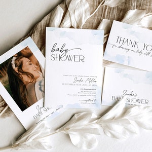May include: A collection of baby shower invitations and thank you cards. The cards feature a watercolor design with soft blue accents and elegant black text. One card includes a photo of a smiling person. The text includes the words "baby shower" and "thank you".