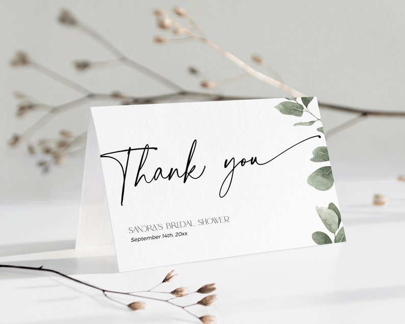 Może przedstawiać: Biała kartka z podziękowaniem z czarną kaligrafią, na kt&oacute;rej widnieje napis "Dziękuję" oraz tekst "Sandra's Bridal Shower September 14th 20xx". Kartka ma zielony akwarelowy wz&oacute;r kwiatowy po prawej stronie.