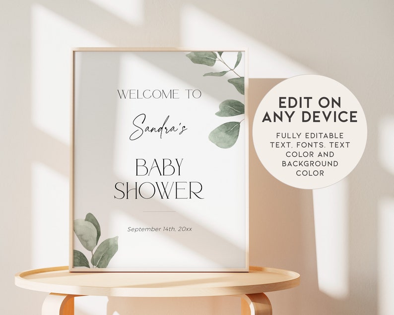 May include: A printable sign for a baby shower with a white background and green eucalyptus leaves. The text reads "Welcome to Sandra's Baby Shower September 14th, 20xx".