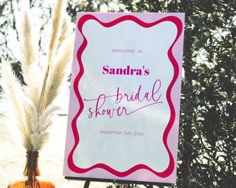 May include: Pink and white sign with a wavy border, announcing "Welcome to Sandra's bridal shower" with the date "September 14th, 20xx".