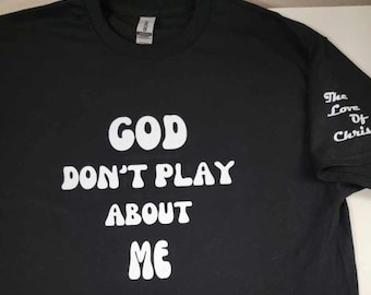May include: Black t-shirt with white text that reads "GOD DON'T PLAY ABOUT ME". The right sleeve has white text that reads "The Love Of Chris".