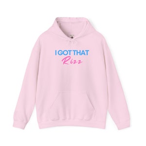 May include: A pink hoodie with a blue and pink graphic that says "I GOT THAT Rizz"