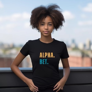 May include: A black t-shirt with the text "ALPHA. BET." in yellow and blue lettering.