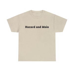 May include: A beige t-shirt with the text "Hazard and Main" printed in black on the front.