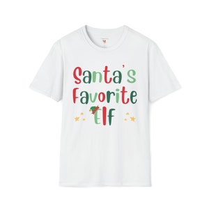 May include: White t-shirt with a green, red, and yellow graphic that says "Santa's Favorite Elf" with a small elf hat graphic.