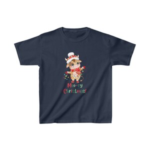 May include: Navy blue t-shirt featuring a cartoon cow wearing a Santa hat, scarf, and holding Christmas lights. The text "Moo-ry Christmas!" is printed below the cow in red and green.