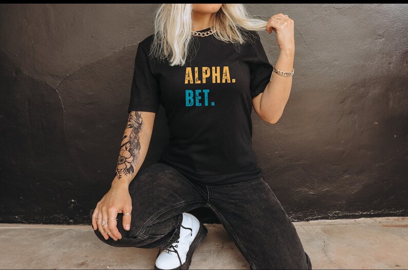 May include: A black t-shirt with the text "ALPHA. BET." in yellow and blue lettering.