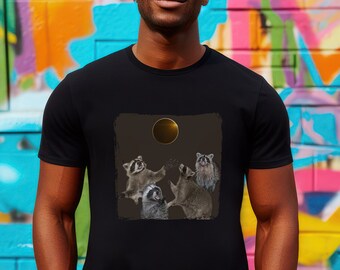 May include: A black t-shirt with a graphic of four raccoons looking up at a golden ring in the sky. The raccoons are in a playful pose, with their paws raised in the air.