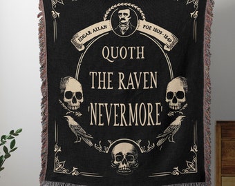 Può includere: Una coperta tessuta nera con un ritratto color crema di Edgar Allan Poe, il testo 'QUOTH THE RAVEN NEVERMORE', tre teschi umani e due corvi. La coperta presenta un bordo decorativo e frange su tutti i lati.