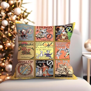 May include: A yellow throw pillow with a collage of vintage book covers featuring the "Oz" series by L. Frank Baum. The covers feature illustrations of characters like Dorothy, the Scarecrow, and the Tin Man.