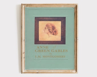 May include: A vintage book cover featuring a woman with red hair in profile. The title is "Anne of Green Gables" by L.M. Montgomery. The cover is framed in a gold frame.