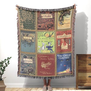 May include: A woven throw blanket featuring a grid of nine classic book covers including Pride and Prejudice, The Iliad, Alice's Adventures in Wonderland, Poe, The Wonderful Wizard of Oz, Arabian Nights, Shakespeare, Grimm's Fairy Tales, and The Great Gatsby.