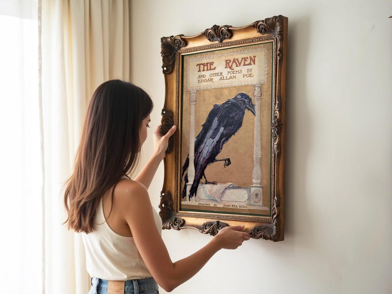 A woman is hanging a framed poster of a raven on a wall.
