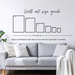 a living room with a gray sofa, a potted plant, and a wall with a wall art guide providing sizes for different artworks.
