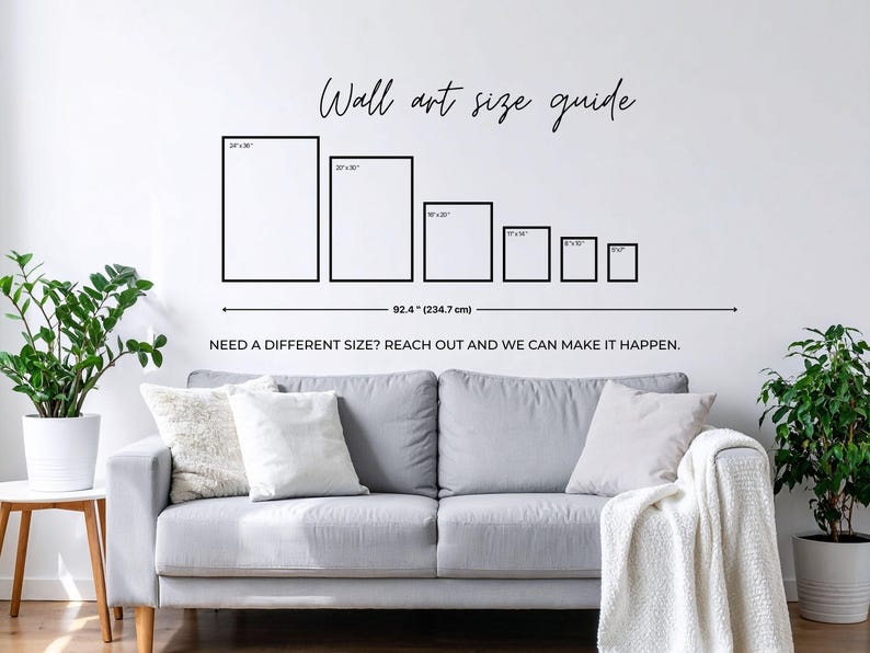 a living room with a gray sofa, a potted plant, and a wall with a wall art guide providing sizes for different artworks.