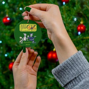a person holding a green ornament in front of a christmas tree