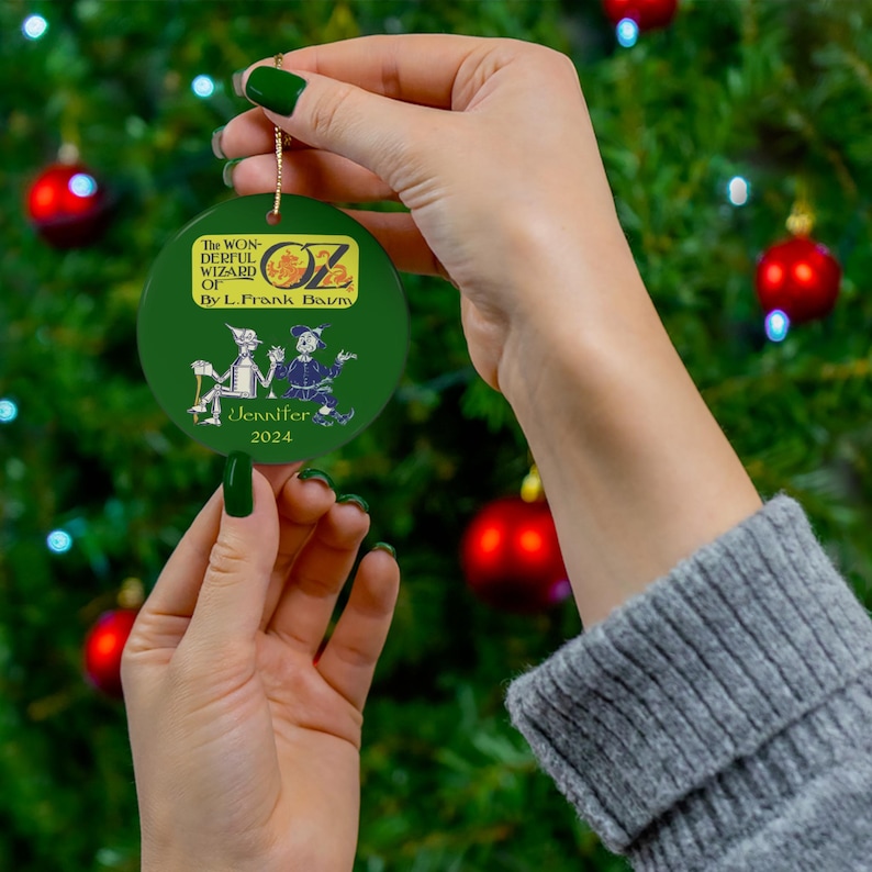 a person holding a green ornament in front of a christmas tree