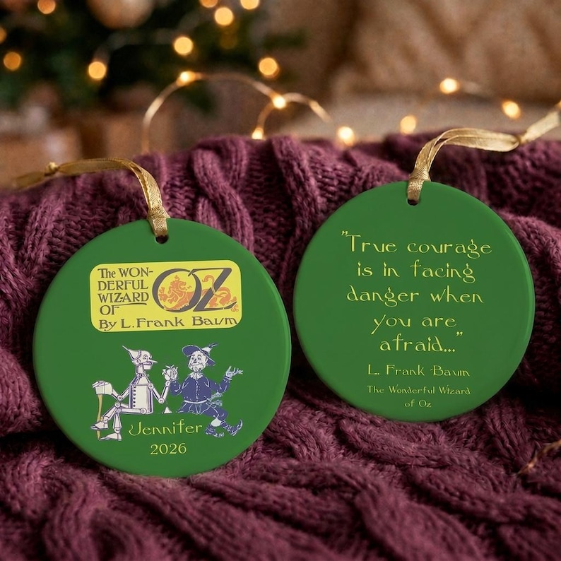 Pu&ograve; includere: Due ornamenti rotondi in ceramica verde con nastri dorati. Uno riporta il testo The Wonderful Wizard of Oz by L. Frank Baum, illustrazioni dell'Uomo di Latta e dello Spaventapasseri, il nome Jennifer e 2026. L'altro mostra la citazione True courage is in facing danger when you are afraid... di L. Frank Baum.