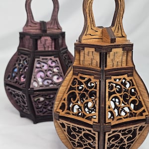 May include: Two wooden lanterns with intricate cut-out designs. One is stained a dark reddish-brown, the other a natural wood tone. Both have arched handles and geometric shapes with decorative patterns, perfect for home decor.