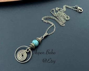 May include: A turquoise stone bead necklace with a spiral charm and a silver chain. The necklace is on a dark background with the text "Aspen Boho @Etsy".