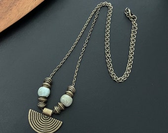 May include: A silver chain necklace with a half-circle pendant and two light green beads.