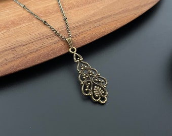 May include: A delicate gold-toned pendant necklace with a filigree design. The pendant is shaped like a teardrop and features intricate details.