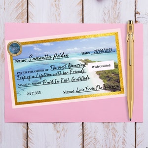 May include: A mock-up of a wish granted cheque with a tropical beach scene. The cheque is made out to Samantha Holden for "The most Amazing Trip of a Lifetime with her Friends." The cheque is dated 21/06/2023 and signed "Love From The Universe".