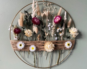 Boho gold hoop with dried flowers for naturalistic interiors. Metal ring with jute cord and blooms in farmhouse style.