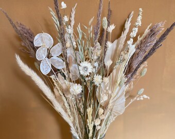 A large boho bouquet with dried flowers and grasses. A sunny home decoration adding warmth to boho interiors.