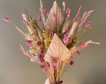 A large spring bouquet with dried flowers and grasses. A sunny home decoration adding warmth to boho interiors.