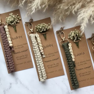 The macrame keychain is attached to the kraft card. There are white flowers on the customizable card.
