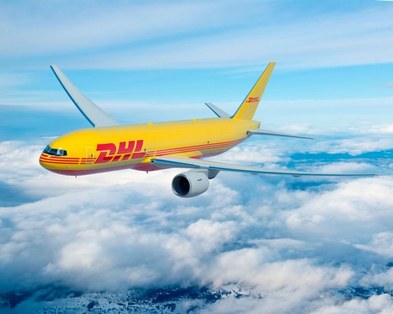 May include: A yellow DHL cargo airplane flies through a cloudy sky. The plane has the DHL logo in red and yellow on its side. The wings are extended, and the plane is in mid-flight.