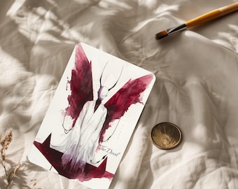 May include: A tarot card featuring a watercolor illustration of a figure with red wings and the text "The Devil". The card is on a white surface, with a gold coin and paintbrush nearby.