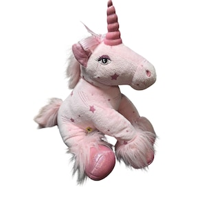 May include: A plush unicorn toy in a light pink color featuring a spiral horn, a soft mane, and a tail. The body is covered in a pattern of small dark pink stars. It has embroidered eyes with long eyelashes and shiny pink fabric on its hooves.