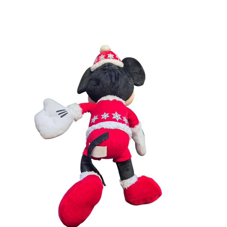 Op de afbeelding: Een pluche Mickey Mouse-speelgoed gekleed in een rood kerstoutfit met witte sneeuwvlokaccenten. Het speelgoed heeft zwarte oren, een rode hoed en witte handschoenen. Het speelgoed is ongeveer 46 cm hoog.