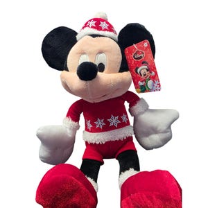 Op de afbeelding: Een pluche Mickey Mouse-speelgoed in een rood kerstoutfit met witte randen en sneeuwvlokken. Het speelgoed heeft een bijpassende hoed en grote rode voeten. Een Disney-label is bevestigd.