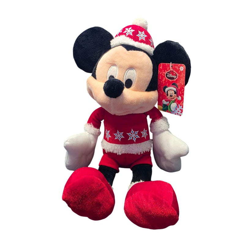 Op de afbeelding: Een pluche Mickey Mouse-speelgoed in een feestelijke kerstoutfit. De rode outfit heeft witte sneeuwvlokaccenten en -afwerking, met een bijpassende hoed. Het speelgoed heeft zwarte oren, een zwarte neus en witte handschoenen en voeten. Een Disney-label is bevestigd.