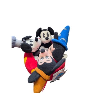 May include: A collection of Mickey Mouse plush toys in various poses. One Mickey is wearing a blue wizard hat with stars, another is in a classic pose, and a third is upside down. The toys are in red, black, white, and yellow.