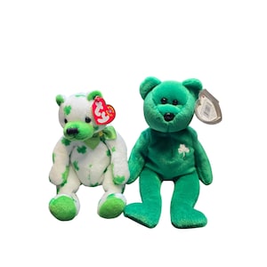 May include: Two plush teddy bears. One is white with green shamrocks and accents, the other is solid green. Both have tags attached. The bears are sitting upright.