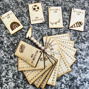 Könnte beinhalten: Holz-Lernkarten mit geätzten Illustrationen und Multiplikationstabellen. Die Karten zeigen einen Regenbogen, einen Fußball, Wimpelketten und eine Karotte. Der Text "DAS KLEINE 1x1 VON" ist auf den Karten aufgedruckt.