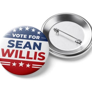 May include: A pair of campaign buttons. One button is face up, displaying the text "VOTE FOR SEAN WILLIS" in blue and red, with stars. The other button is face down, showing the silver pin back.