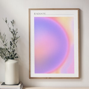May include: A framed print with a gradient background of pink, purple, and yellow. The text "RADIATE" is at the top of the print.