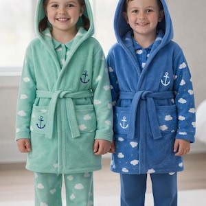 Könnte beinhalten: Zwei Kinder in passenden Kapuzenbademänteln und Pyjamas. Eines trägt einen mintgrünen Bademantel und Pyjama mit weißen Wolken- und Ankerdesigns. Das andere trägt einen blauen Bademantel und Pyjama mit weißen Wolken- und Ankerdesigns.