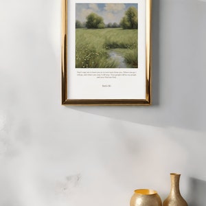 Op de afbeelding: Een ingelijste print met een aquarel van een groen veld met een beekje erdoorheen. Onder de afbeelding staat de quote "Dring me niet om je te verlaten of om terug te keren van je. Waar je heen gaat, ga ik heen, en waar je blijft, blijf ik. Je volk zal mijn volk zijn en jouw God mijn God." gedrukt, met de naam "Ruth 1:16" onderaan.
