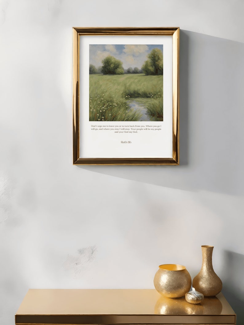 Op de afbeelding: Een ingelijste print met een aquarel van een groen veld met een beekje erdoorheen. Onder de afbeelding staat de quote "Dring me niet om je te verlaten of om terug te keren van je. Waar je heen gaat, ga ik heen, en waar je blijft, blijf ik. Je volk zal mijn volk zijn en jouw God mijn God." gedrukt, met de naam "Ruth 1:16" onderaan.