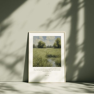Op de afbeelding: Een ingelijste print van een schilderij dat een groene weide met een klein beekje erdoorheen afbeeldt. De lucht is blauw met witte wolken. De print bevat een citaat uit de Bijbel: "Ween niet over mij dat ik je verlaat, of keer niet van je af. Waar je heen gaat, zal ik gaan, en waar je blijft, zal ik blijven. Je volk zal mijn volk zijn en je God mijn God." - Ruth 1:16